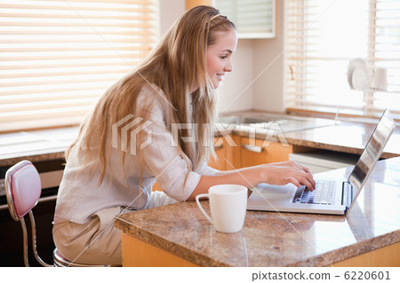 Woman having coffee while using a notebook Woman having coffee while using a notebook 6220601