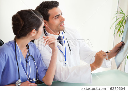 Professional doctors looking at a set of X-ray 6220604