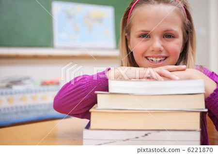 Schoolgirl posing with a stack of books 6221870
