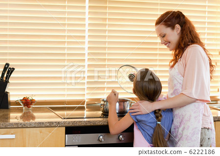 Cheerful mother showing her daughter how to cook 6222186