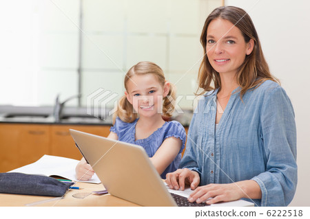 Girl doing her homework while her mother is working with laptop 6222518