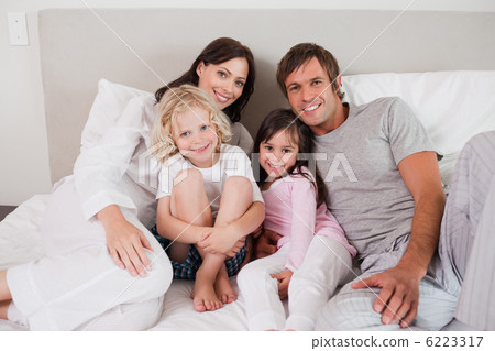 Smiling family posing on a bed 6223317