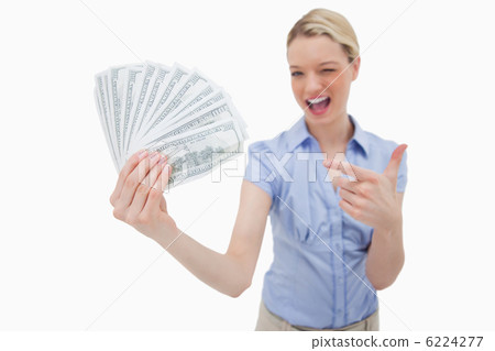 Woman holding money and pointing at it 6224277