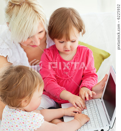 Cheerful family having fun with a laptop in the living-room Cheerful family having fun with a laptop in the living-room 6225932
