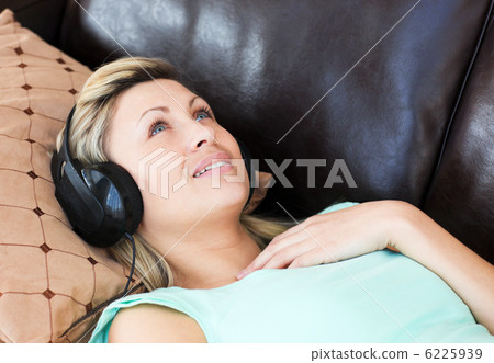 Young woman lies on a sofa and listen music Young woman lies on a sofa and listen music 6225939