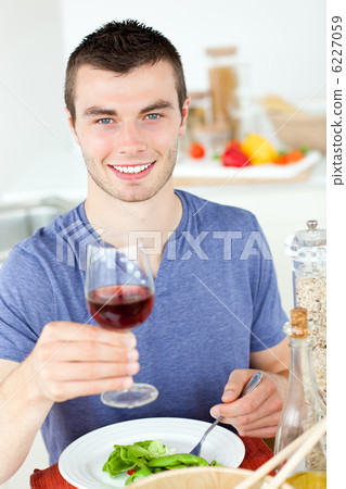 Cute man eating a healthy salad with some wine 6227059