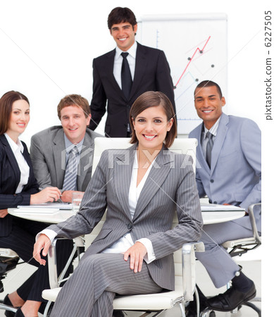 Assertive female executive sitting in front of her team 6227505
