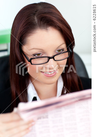 Glowing young businesswoman reading a newspaper Glowing young businesswoman reading a newspaper 6228615