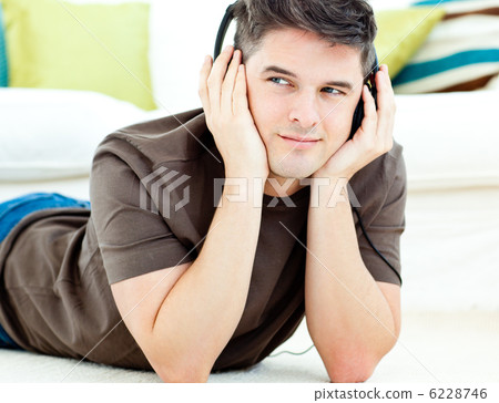 Attractive man listen to music lying on the floor Attractive man listen to music lying on the floor 6228746