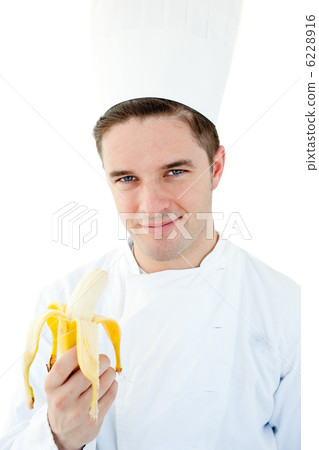 Charming male cook holding banana smiling at the camera 6228916