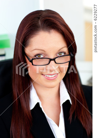 Bright businesswoman holding her glasses sitting in her office 6229277