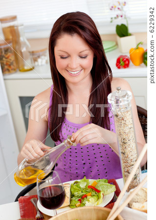Bright woman eating a salad with oil in the kitchen Bright woman eating a salad with oil in the kitchen 6229342
