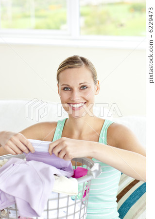Cheerful young woman doing the laundry Cheerful young woman doing the laundry 6229473