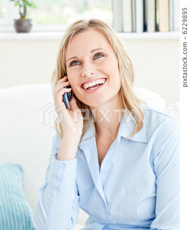 Joyful businesswoman talking on phone sitting on a sofa 6229895
