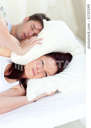 Young woman annoyed by the snores of her boyfriend in the bedroo Young woman annoyed by the snores of her boyfriend in the bedroo 6230340