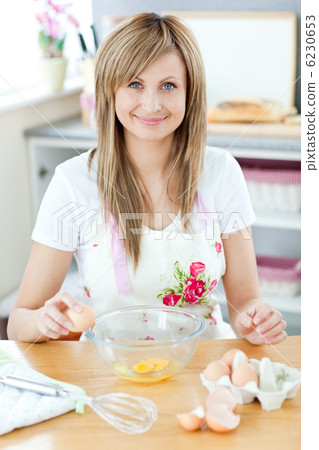 Joyful woman cooking in the kitchen and breaking eggs Joyful woman cooking in the kitchen and breaking eggs 6230653
