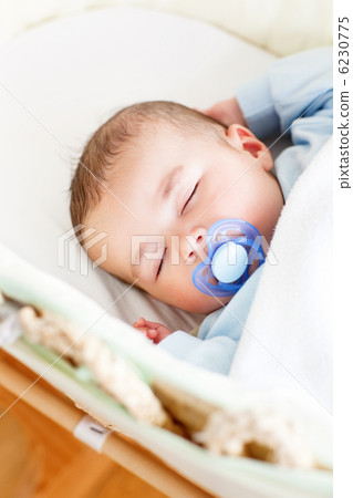 Portrait of a sleeping baby lying in his cradle with his dumm Portrait of a sleeping baby lying in his cradle with his dumm 6230775