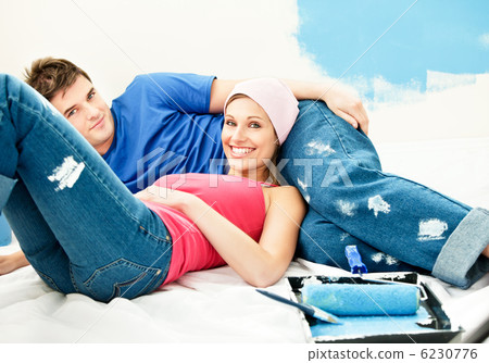 Happy young couple relaxing after painting a room Happy young couple relaxing after painting a room 6230776