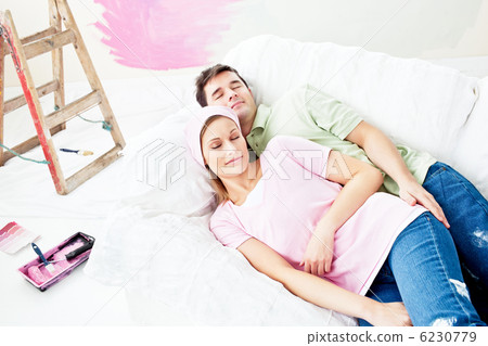 Positive caucasian couple sleeping on a sofa after painting a ro Positive caucasian couple sleeping on a sofa after painting a ro 6230779