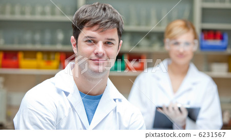 Two concentrated scientists looking at the camera standing Two concentrated scientists looking at the camera standing 6231567