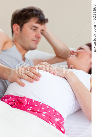Joyful caucasian pregnant woman lying on bed with her husband 6231666