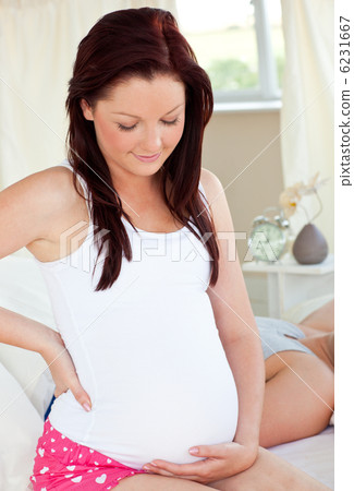 Positive pregnant woman touching her belly in the bedroom 6231667