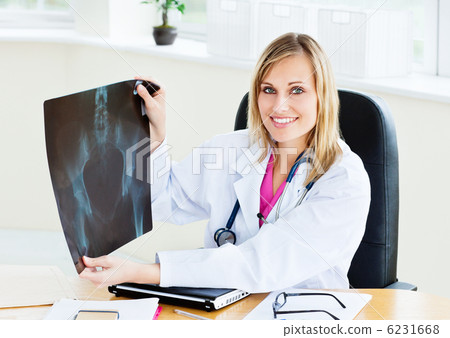 Beautiful female doctor showing an x-ray to the camera sitting i 6231668