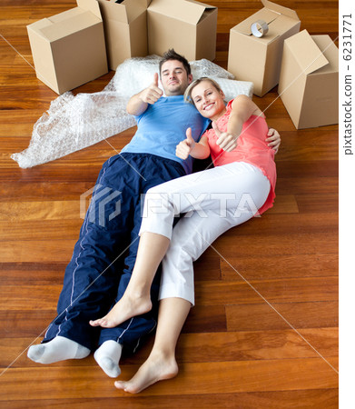 happy couple lying on the floor in their new house doing thumbs- happy couple lying on the floor in their new house doing thumbs- 6231771