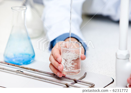 Close-up of a male scientist pouring liquid into a becher Close-up of a male scientist pouring liquid into a becher 6231772