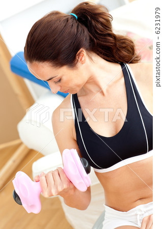 Athletic hispanic woman holding a dumbbell in her living-room Athletic hispanic woman holding a dumbbell in her living-room 6231979