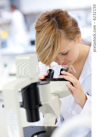 Serious female scientist using a microscope 6232150