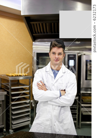 Proud baker standing in his kitchen bending his arms waiting for 6232173