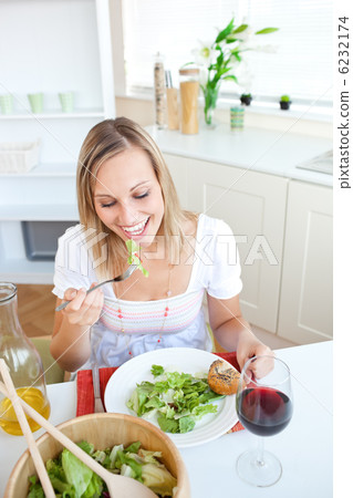 Portrait of a beautiful woman eating a salad in the kitchen Portrait of a beautiful woman eating a salad in the kitchen 6232174
