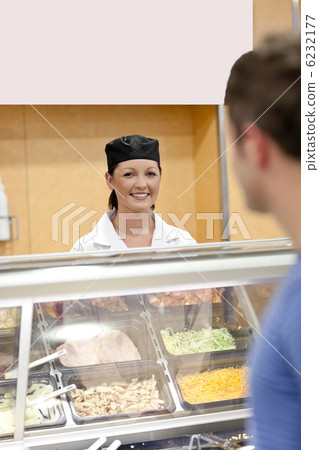 Beautiful cook standing behind the refrigerated display in a caf Beautiful cook standing behind the refrigerated display in a caf 6232177