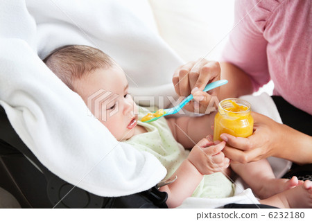 Close-up of a young mother giving carrot puree to her baby for l Close-up of a young mother giving carrot puree to her baby for l 6232180