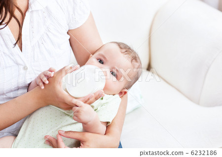 Close-up of a baby in his mother's arms drinking milk for lunch Close-up of a baby in his mother's arms drinking milk for lunch 6232186