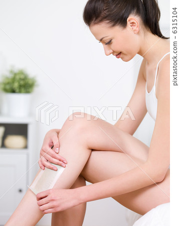 Woman depilating her legs by waxing Woman depilating her legs by waxing 6315104