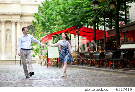 Couple walking in Paris near an outdoor cafe 6317419
