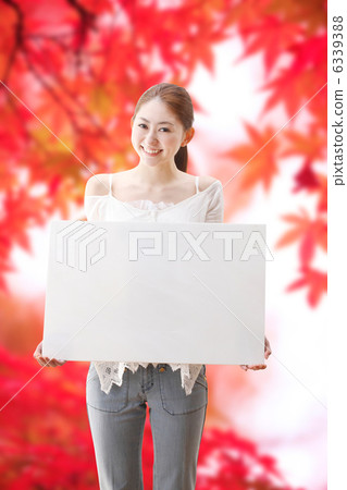 有一個白板和秋葉的一名婦女 有一個白板和秋葉的一名婦女 6339388