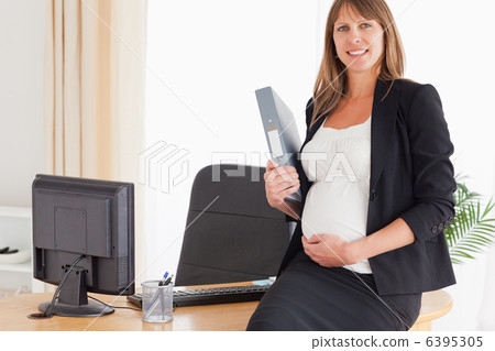 Pretty pregnant female holding a file while standing Pretty pregnant female holding a file while standing 6395305