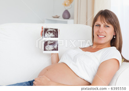 Happy pregnant woman showing her babys ultrasound scan 6395550