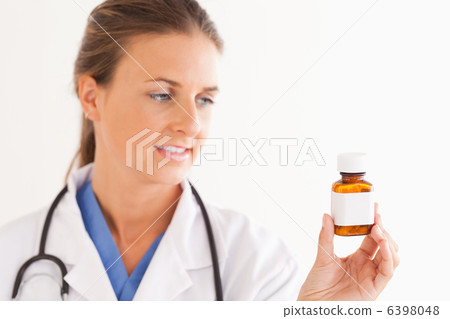 Portrait of a smiling doctor looking at some pills 6398048