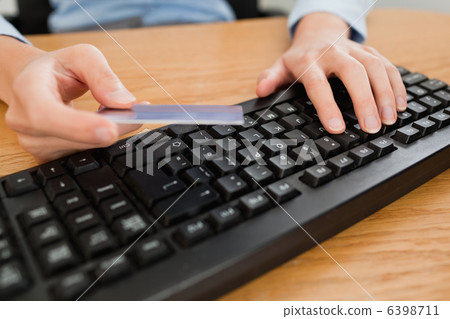 Woman typing on keyboard holding a credit card 6398711