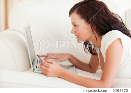 Cute woman working on a laptop with a credit card Cute woman working on a laptop with a credit card 6398870