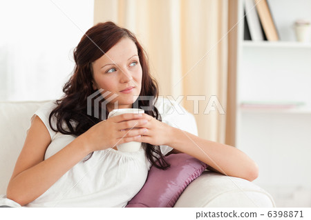 Portrait of a woman holding a cup looking out the window 6398871