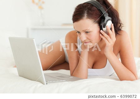 Woman listening to music working on a laptop Woman listening to music working on a laptop 6399072