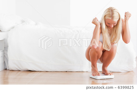Cheerful woman squatting on a weighing machine Cheerful woman squatting on a weighing machine 6399825