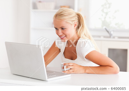 Cute woman having a cup of tea while using her notebook Cute woman having a cup of tea while using her notebook 6400085