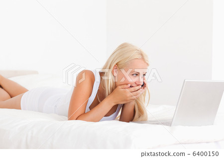 Woman laughing on the phone while using a laptop 6400150