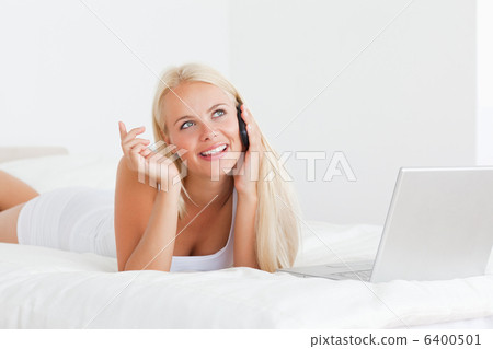 Smiling woman speaking to the phone with a laptop Smiling woman speaking to the phone with a laptop 6400501